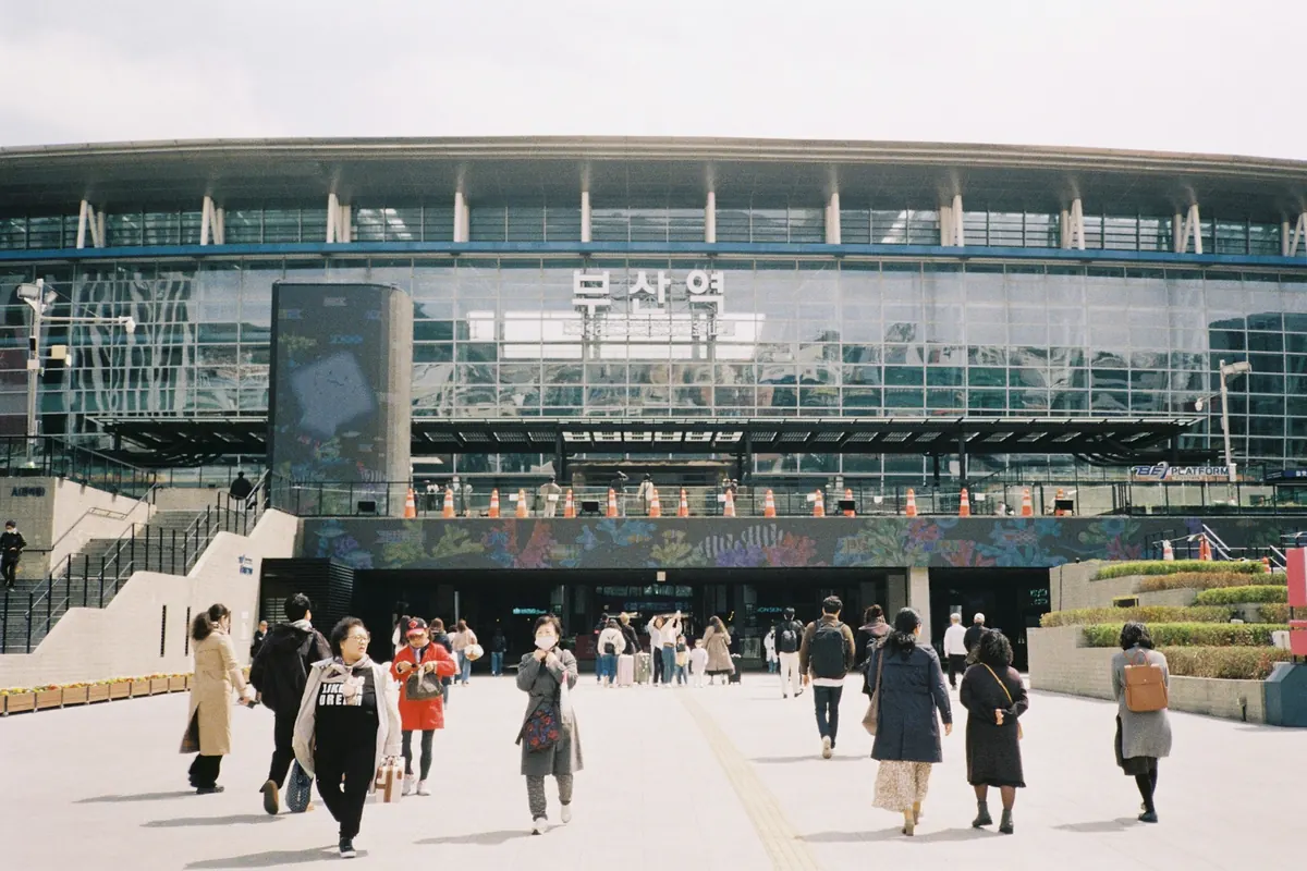 부산역으로 걸어 들어가는 사람들과 현대적인 역 외관
